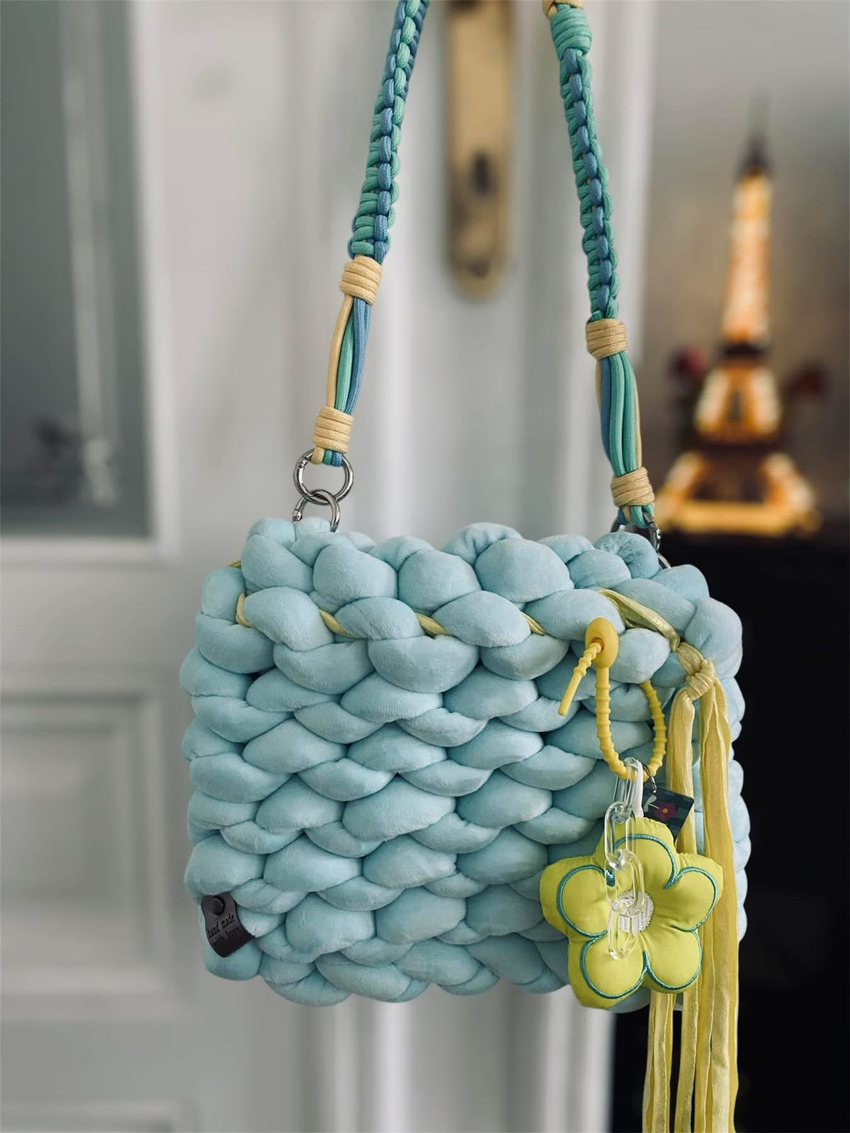 Nani Sky Bloom — pale blue chunky knit bag with braided cord strap and yellow flower charm